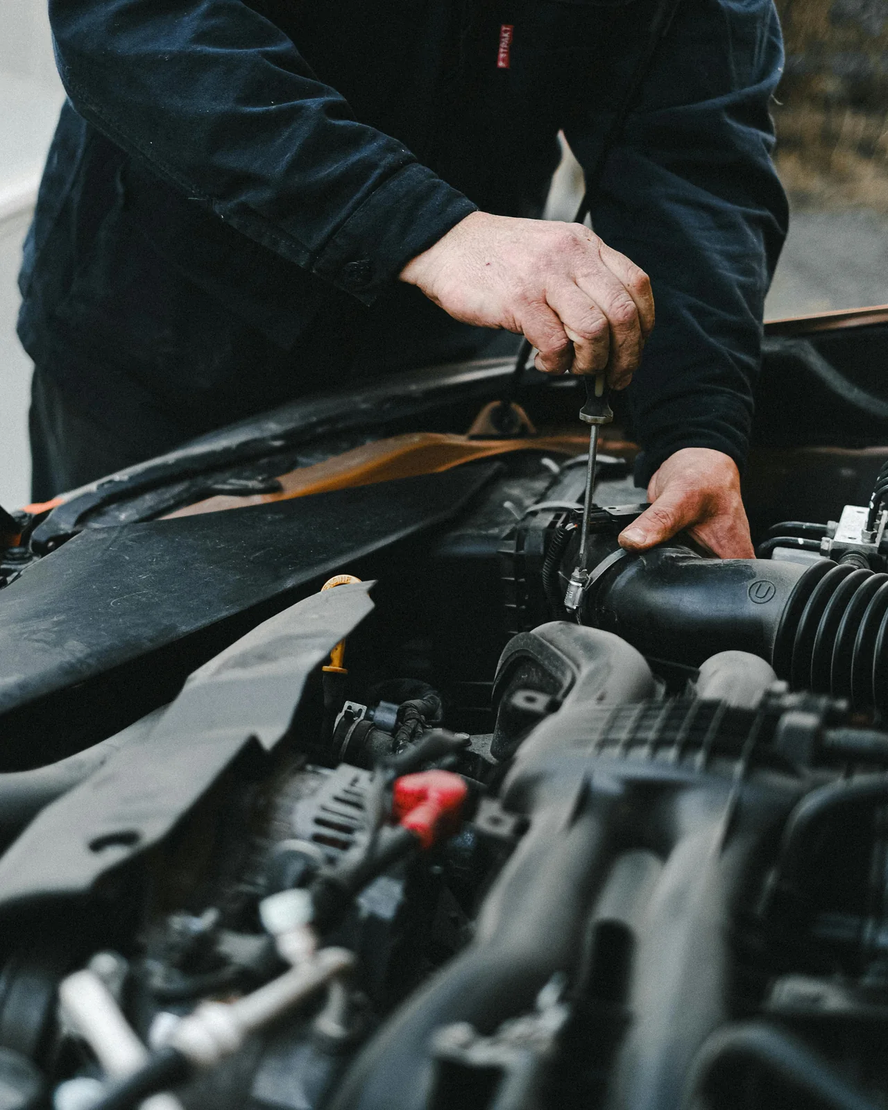 A technician working under the hood of a car